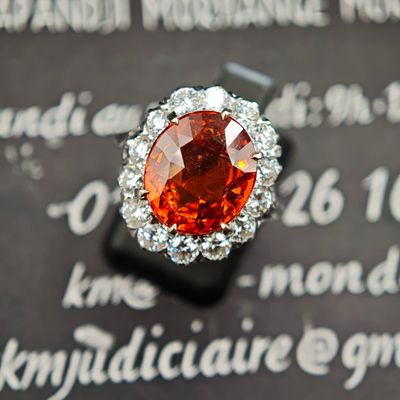une bague sertie d'un diamant orange, posée sur un morceau de papier