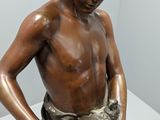 bronze statue of a boy holding a book on a white surface