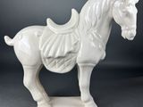 white horse figurine with saddle on stand on grey background