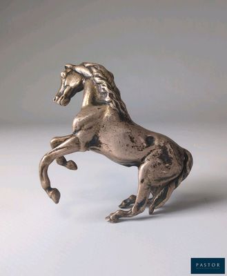 statue en argent représentant un cheval dressé sur ses pattes arrière, posée sur une surface blanche