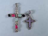 deux pendentifs en forme de croix ornés de pierres multicolores sur un fond blanc