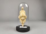 une figurine représentant une femme corpulente, exposée sous une cloche en verre