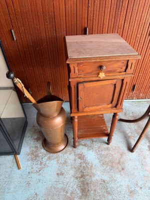 une armoire en bois et un vase en métal posés contre un mur