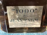jean patou perfume bottle on a table with a blue table cloth