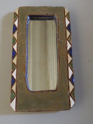 a small mirror sitting on a table next to a wall