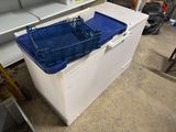 a white chest freezer with a blue basket on top of it