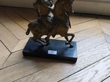 a statue of a man riding a horse on a wooden base