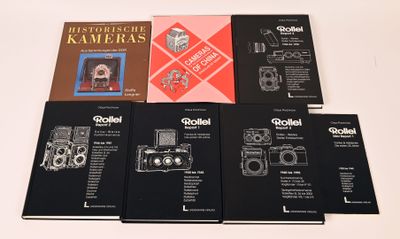 six livres posés sur une table blanche, avec un appareil photo posé dessus