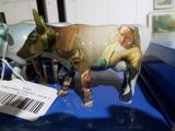 Des figurines représentant une femme et une vache sont exposées dans une vitrine.