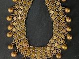 un collier en or orné de clochettes et de perles sur fond noir