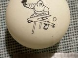 une balle blanche sur laquelle est dessiné un homme jouant au ping-pong