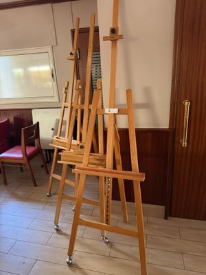 a easel in the middle of a room with chairs and a table
