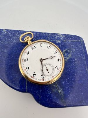 a gold pocket watch sitting on top of a blue marble slab