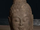 statue of a buddha head on a table with a dark background