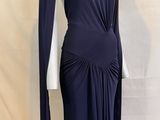 une femme vêtue d'une robe bleue et d'une cape est debout sur un mannequin
