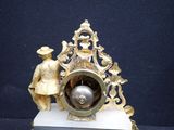 a clock that is sitting on a stand with a man standing next to it