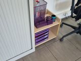 a desk with a chair and a shelf in the corner