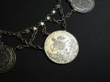 a necklace with coins on it on a black surface