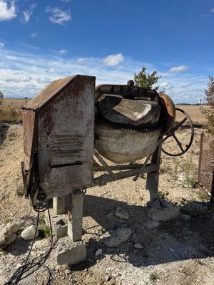 une bétonnière garée au milieu d'un champ de terre battue