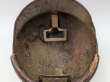 an old, rusty helmet with a metal handle on a white surface