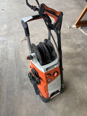 une machine à pression électrique orange et noire posée sur un sol en béton