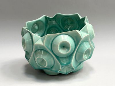 a green bowl with a design on it on a white surface