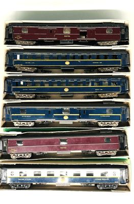 Plusieurs trains miniatures sont alignés les uns à côté des autres sur une surface blanche