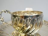 a silver cup and saucer on a silver plate