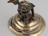 brass figurine of a dog on a pedestal on a white background