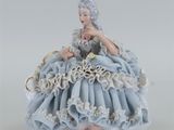figurine en porcelaine représentant une femme en robe bleue tenant une fleur