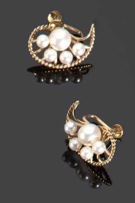 deux paires de boucles d'oreilles en perles et en or posées sur un fond noir