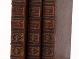 trois vieux livres posés l'un sur l'autre sur une table