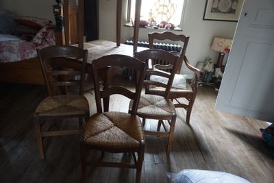 une table et six chaises dans une pièce où l'on aperçoit un lit à l'arrière-plan