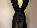 une robe en cuir noir posée sur un mannequin contre un mur blanc