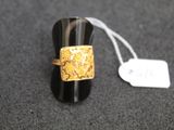 a black ring with a gold design on it and a price tag