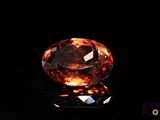 a close up of an orange diamond on a black surface