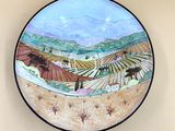 une assiette sur laquelle est représenté un paysage