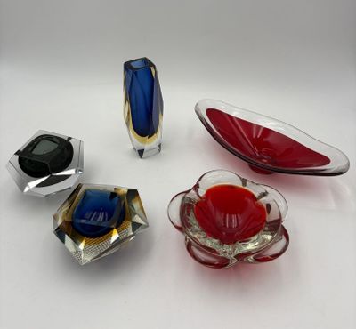 four different colored glass objects are arranged on a white surface