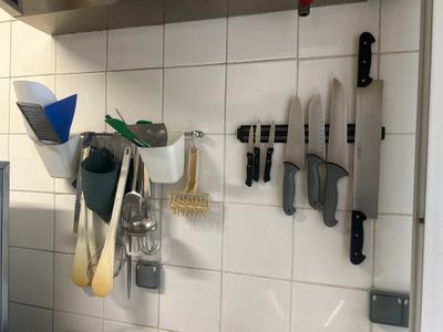 many knives and spoons hanging on the wall in the kitchen