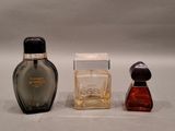 two small bottles of perfume sitting next to each other on a white surface