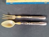 two forks and spoons sitting next to a box of cheese