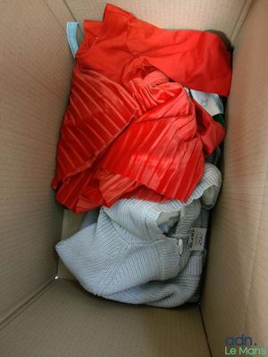 une boîte en carton remplie de vêtements et d'une couverture rouge