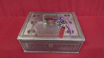 une petite boîte en métal ornée d'un ruban violet
