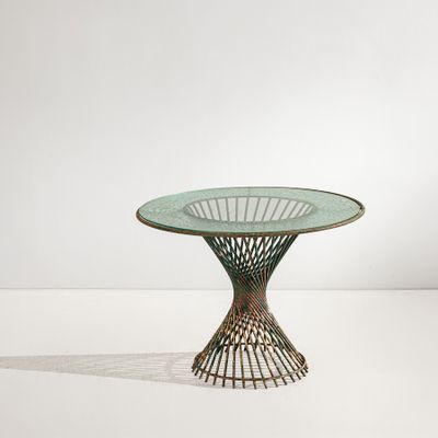 une photo d'une table en verre avec un piètement en métal, posée sur une surface blanche