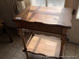 a wooden table with a drawer on it in front of a window