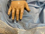 someone is holding a doll in a blue dress with lace on it ' s arm