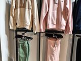 two sets of tracksuits hanging on a rack in a clothing store