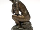 bronze statue of a woman kneeling on a pedestal with her hands on her knees