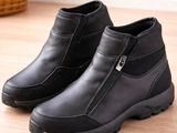 une paire de bottes noires posées sur un parquet, avec un panier en arrière-plan