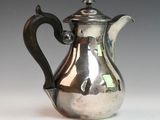 an antique silver coffee pot with a black handle on a white surface